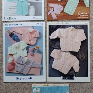 May include: Five different knitting patterns for baby sweaters and cardigans. The patterns are from UKHKA, Studio StyleCraft, Hayfield, and Sirdar. The patterns feature a variety of colours and styles, including pink, blue, and white.