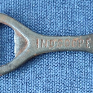 May include: A rusty metal bottle opener with a hole in the handle and the word "INSCOOPE" printed on it.