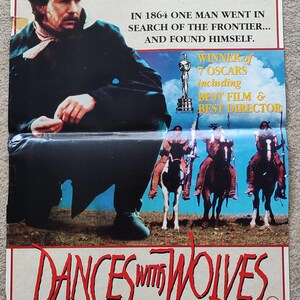 May include: A movie poster for the film Dances with Wolves, starring Kevin Costner. The poster features a close-up of Costner in character, with a backdrop of a blue sky and a grassy field. The text on the poster reads "Kevin Costner", "In 1864 one man went in search of the frontier... and found himself.", "Winner of 7 Oscars including Best Film & Best Director", and "Dances with Wolves".