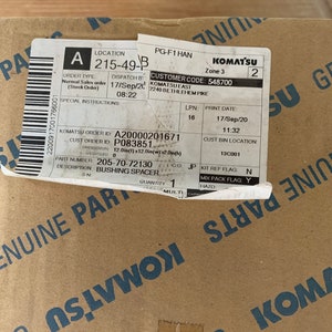 Pu&ograve; includere: Una scatola di cartone marrone con un'etichetta bianca che dice "KOMATSU" e contiene le seguenti informazioni d'ordine: "A 215-49-B", "CODICE CLIENTE: 548700", "NUMERO D'ORDINE KOMATSU: A20000201671", "NUMERO D'ORDINE CLIENTE: P083851", "NUMERO PEZZO: 205-70-72130", "DESCRIZIONE: DISTANZIALE", "QUANTIT&Agrave;: 1".