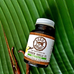May include: A brown glass bottle with a white lid containing Bourbon Vanilla Oil by Kokoa Botanics. The bottle is labeled with the product name, ingredients, and net weight of 2 ounces (56g).