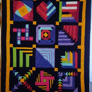 May include: A quilt with a black background and a yellow border. The quilt is made up of nine squares, each with a different geometric design in various colors, including red, blue, green, and purple.