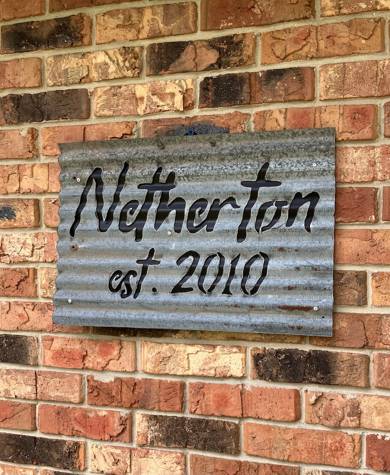 May include: A corrugated metal sign with the name "Netherton" cut out in a bold, black font, with "est. 2010" below. The sign is mounted on a brick wall, showcasing a rustic, industrial aesthetic.