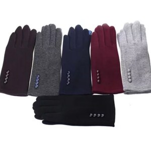 Può includere: Sei paia di guanti in diversi colori, tra cui grigio, bordeaux, blu navy e nero. I guanti sono realizzati in un tessuto morbido e lavorato a maglia e hanno un dettaglio a bottone sul polso.