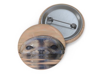 May include: A close-up of a seal's face peeking out of the water. The seal has dark eyes and a wet, black nose. The water is a light brown color.