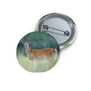 以下が含まれることがあります： 角のあるオジロジカが草地の中に立っています。シカはカメラを直接見ています。背景はぼやけた緑と茶色です。