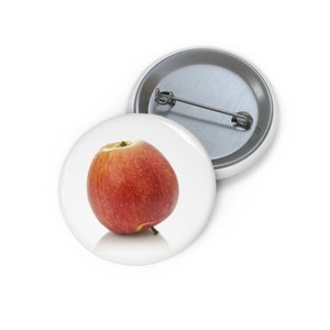 May include: A red apple with a yellow stem and a slight red blush on the side. The apple is sitting on a white surface.