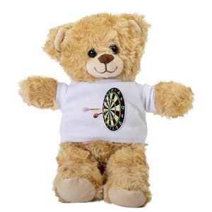 May include: A brown teddy bear wearing a white t-shirt with a dartboard and darts printed on it.