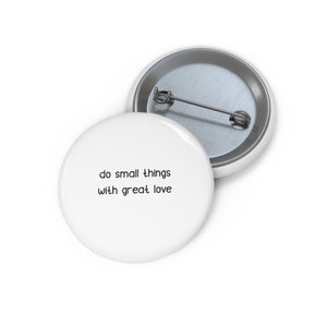 May include: White button with the text "do small things with great love" printed in black.
