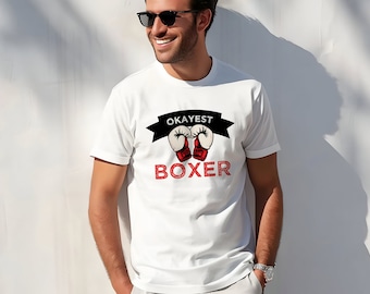 May include: White t-shirt with a black and red graphic of boxing gloves and the text "Okayest Boxer".