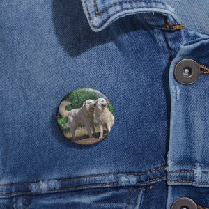 May include: A button featuring a photograph of two white dogs standing side-by-side in a grassy field.