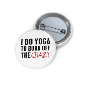 Könnte beinhalten: Weißer Knopf mit schwarzem Text, der "Ich mache Yoga, um den Wahnsinn zu verbrennen" lautet, wobei das Wort "Wahnsinn" in Rot ist.