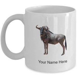 Może przedstawiać: Biały ceramiczny kubek do kawy z ilustracją brązowego i czarnego gnu i tekstem "Your Name Here" nadrukowanym na spodzie.