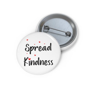 May include: White button with the text "Spread Kindness" in black script with small red hearts scattered around the text.
