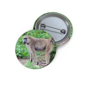 May include: A brown and grey baboon standing in a grassy area. The baboon is looking to the left of the image.