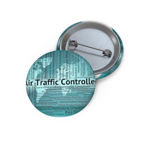 May include: Two round teal and silver pinback buttons. The front of the primary button features the words "Air Traffic Controller" in large white text, surrounded by a word cloud of related job titles. The second button is visible in the background.