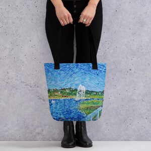 May include: A tote bag with a blue and green painting of a lake with a fountain in the background. The painting is done in a pointillist style.