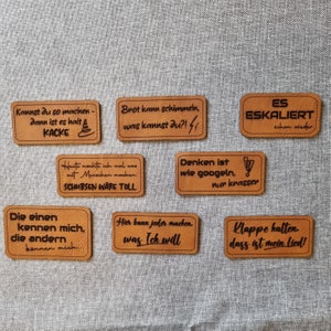 Könnte beinhalten: Neun braune Leder-Patches mit verschiedenen Sprüchen. Die Sprüche lauten: "Kannst du so machen - dann ist es halt KACKE", "Brot kann schimmeln, was kannst du?!", "ES ESKALIERT schon wieder", "Heute mochte ich mal was mit Menschen machen. SCHUBSEN WÄRE TOLL", "Denken ist wie googeln, nur krasser", "Die einen kennen mich, die andern können mich", "Hier kann jeder machen. was Ich will", und "Klappe halten. dass ist mein lied!"