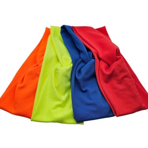May include: Four colorful headbands in bright shades of orange, neon yellow, blue, and red. The headbands are made of soft fabric and are twisted at the top. The headbands are displayed against a white background.
