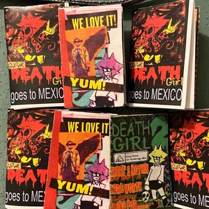 May include: A collection of zines featuring collage-style covers with bold text including "SUPER DEATH GIRL goes to MEXICO", "WE LOVE IT! YUM!", and "DEATH GIRL 2". The graphics display stylized cartoon characters, a winged figure, and various slogans in red, yellow, black, and green.
