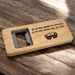 Peut inclure: Un ouvre-bouteille en bois avec un ouvre-bouteille en métal et une citation gravée au laser en français : "Je ne bois jamais à outrance, je ne sais même pas où c'est."