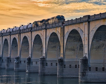 A Print or Canvas of Train crossing the Susquehanna River into Harrisburg PA at sunset.