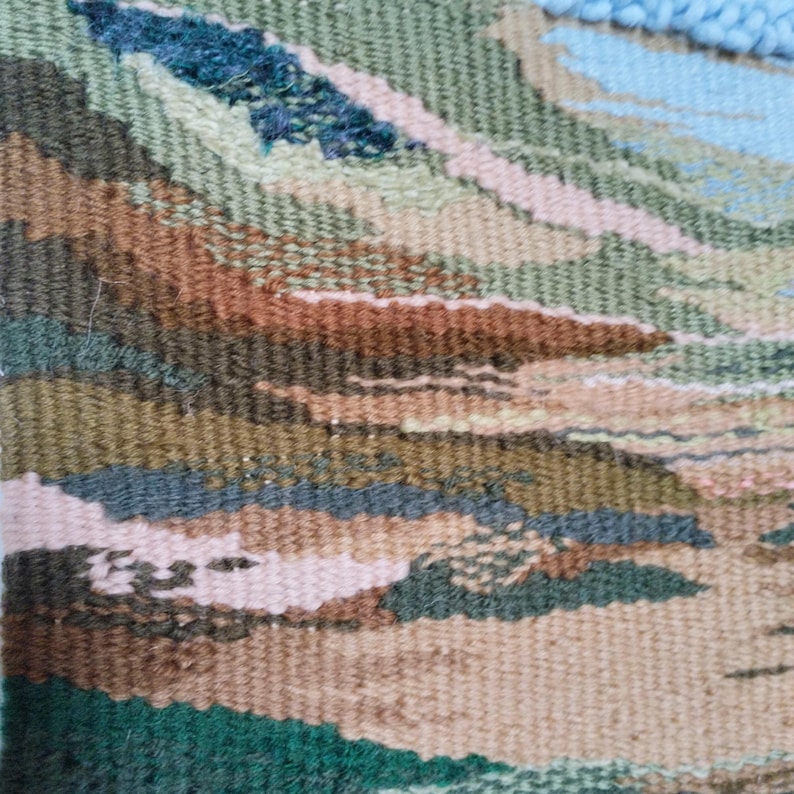 K&ouml;nnte beinhalten: Nahaufnahme einer gewebten Wandteppich mit einem strukturierten, abstrakten Design in Braun-, Gr&uuml;n-, Blau- und Rosat&ouml;nen.