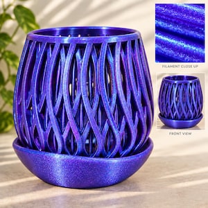 May include: A vibrant purple planter with a shimmering, glittery finish and an intricate, open-weave lattice design. The cylindrical pot sits securely inside a matching circular saucer, showcasing a textured, iridescent surface throughout.
