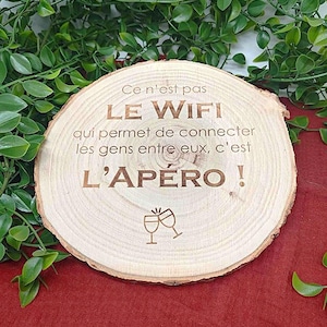 Peut inclure: Une pancarte en bois avec le texte "Ce n'est pas LE WIFI qui permet de connecter les gens entre eux, c'est L'APÉRO!" et un graphique de deux verres à vin qui trinquent.