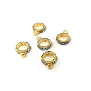 May include: Five gold-toned rings with a black diamond-like stone encrusted band. Each ring has a small loop attached to the side.