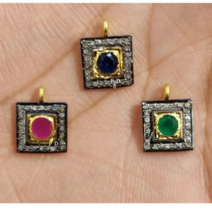 May include: Three square pendants with a gold frame and a single gemstone in the center. The pendants are surrounded by small diamonds. The gemstones are blue, red, and green.