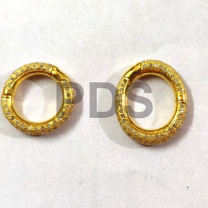 May include: Two gold-toned rings with a circular design. Each ring is adorned with small, white stones that create a sparkling effect.