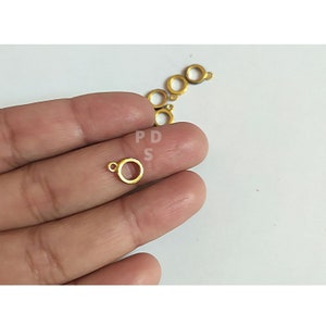 May include: Gold-toned metal jump rings with a small loop on one side. The rings are approximately 1/2 inch in diameter.