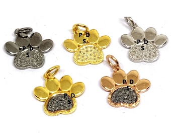 May include: Five paw print charms with black diamonds in the centre. The charms are made of silver, gold, and rose gold.