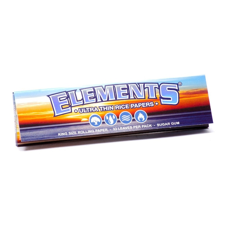Op de afbeelding: Een pak Elements Ultra Thin Rice Papers, kingsize rolpapier met een zonsondergang en oceaan sc&egrave;ne. Het pak bevat 33 blaadjes en heeft suikergom.