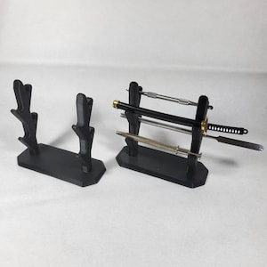 May include: Two black plastic stands for displaying swords and other small blades. One stand has three slots and the other has four slots.