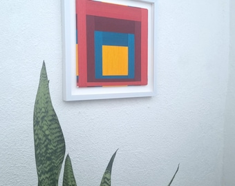 Könnte beinhalten: Ein gerahmtes abstraktes geometrisches Kunstwerk mit einem Farbschema aus Rot, Maroon, Blau und Gelb.