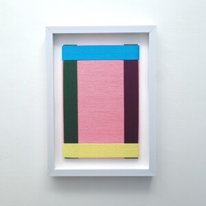 May include: A framed abstract art piece with a pink background and colourful stripes of blue, green, and yellow.