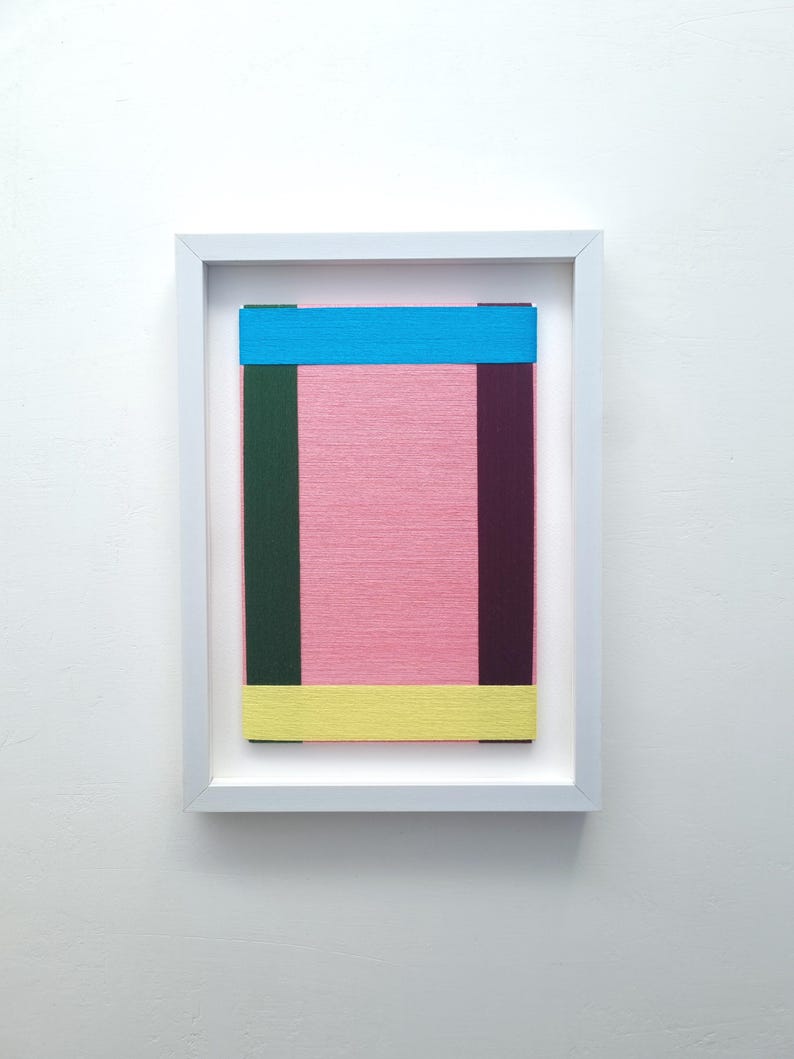 May include: A framed abstract art piece with a pink background and colourful stripes of blue, green, and yellow.
