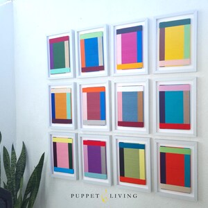 May include: A wall gallery of 12 framed abstract paintings. Each painting features a different combination of colourful geometric shapes and patterns.