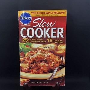 May include: A Pillsbury Slow Cooker cookbook with a red and white cover. The cover features the text "Slow Cooker" in large letters, along with the Pillsbury logo and images of lasagna. The book promises 25 recipes with 15-minute prep and 15 low-fat recipes.