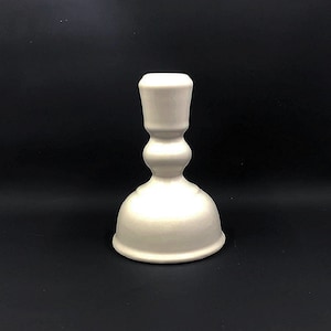 May include: A white ceramic candle holder with a wide base and a narrow top. The holder has a smooth, glossy finish.