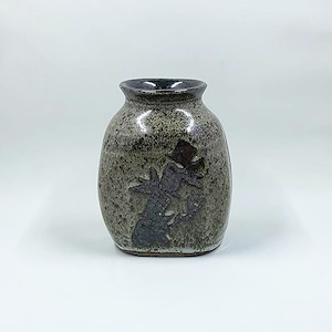 May include: A small, gray ceramic vase with a speckled glaze. The vase has a dark brown rim and a whimsical design of a figure wearing a top hat.