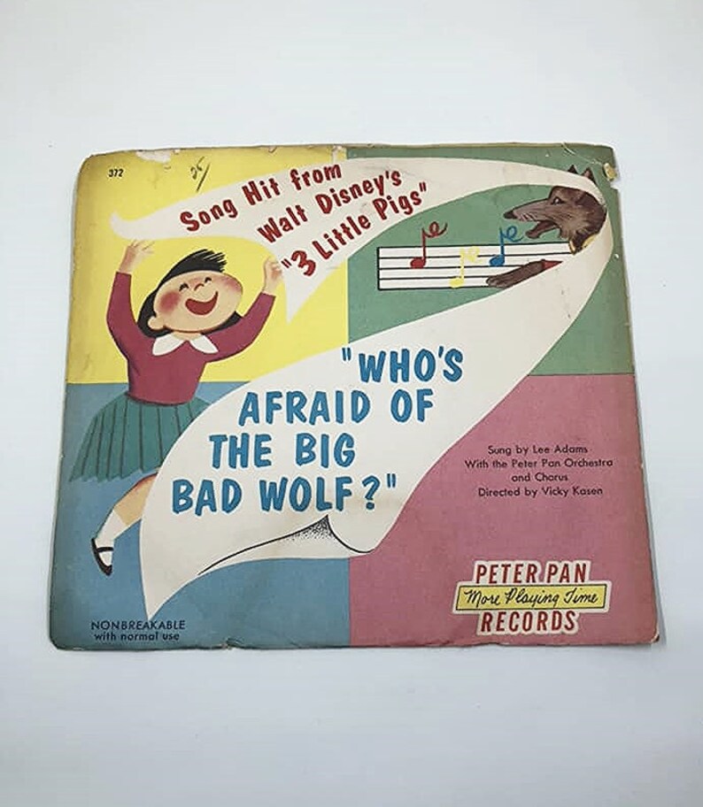 May include: A vintage record sleeve featuring a cartoon illustration of a girl and a wolf. The record is from Walt Disney's "3 Little Pigs" and features the song "Who's Afraid of the Big Bad Wolf?" by Lee Adams. The record is a Peter Pan More Playing Time record.