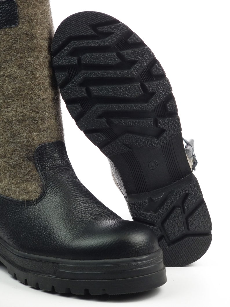 Puede incluir: Una bota alta con una secci&oacute;n inferior de cuero negro texturizado y una ca&ntilde;a superior de lana afieltrada gris. La suela de goma negra tiene un patr&oacute;n de tacos profundos para mayor tracci&oacute;n, con el n&uacute;mero 43 grabado en el centro.