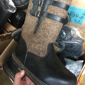 Puede incluir: Botas de fieltro marr&oacute;n con detalles de cuero negro y una suela gruesa de goma negra. Las botas tienen dos hebillas en la parte superior del eje.