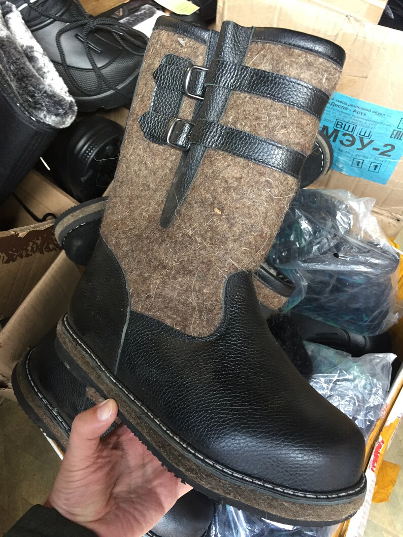 Puede incluir: Botas de fieltro marr&oacute;n con detalles de cuero negro y una suela gruesa de goma negra. Las botas tienen dos hebillas en la parte superior del eje.