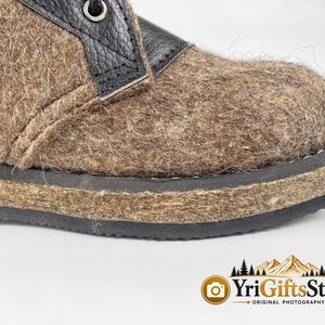 May include: A brown felted wool boot featuring a black leather lace-up panel with a metal eyelet. The boot has a thick, textured brown felt midsole and a black rubber outsole. The design includes a visible seam along the side of the upper.