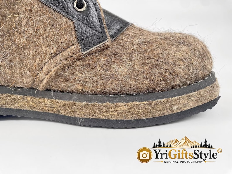 May include: A brown felted wool boot featuring a black leather lace-up panel with a metal eyelet. The boot has a thick, textured brown felt midsole and a black rubber outsole. The design includes a visible seam along the side of the upper.