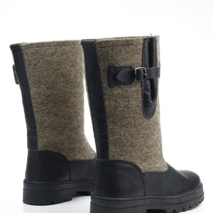 Puede incluir: Un par de botas de media ca&ntilde;a con parte superior de fieltro gris texturizado y ribetes de cuero negro. Las botas incluyen tal&oacute;n y puntera de cuero negro, una suela de goma negra con tacos y una correa de cuero con hebilla met&aacute;lica.